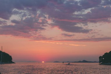Hırvatistan 'ın Cavtat kasabasından izlenen adaların ve teknelerin siluetleriyle Adriyatik Denizi üzerinde gün batımı