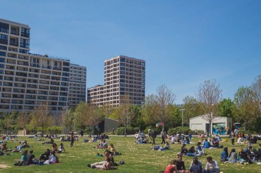 Paris, Fransa - 25 Nisan 2021: Yerel halk Martin-Luther-King Parkı 'nda üçüncü ulusal tecrit sırasında güneşli bir öğleden sonra geçiriyor