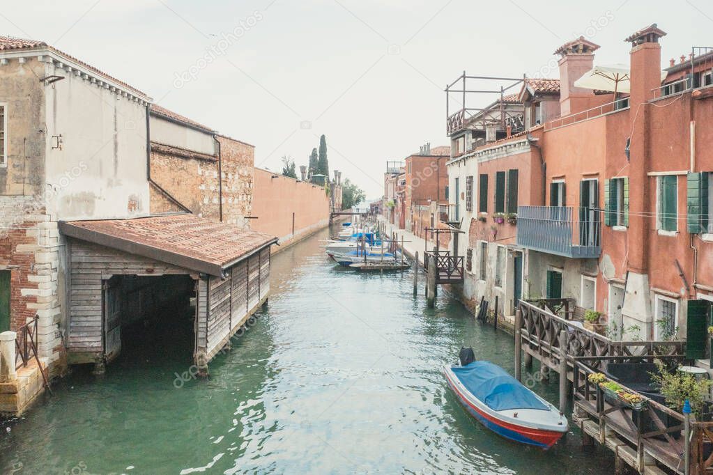 Narrow canal by traditional Venetian houses on island of Giudecca in Venice, Italy