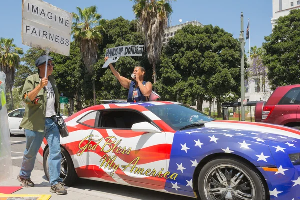 People holding sign next to a car painted in american flag color