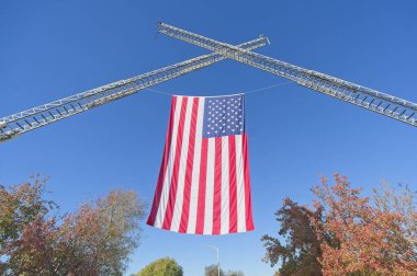 Los Angeles, California, ABD 7 Aralık 2025 - Amerikan bayrağı Pazar günü Supercar 'ın araba fuarında itfaiye merdivenlerinde sıkıştı.