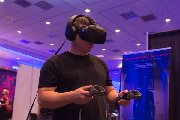 Man tries virtual reality HTC Vive headset and hand controls — Stock Fotó