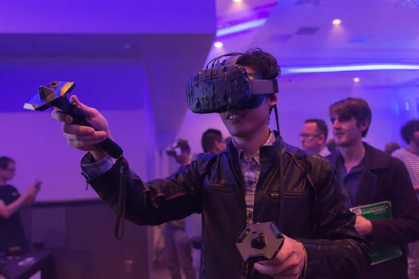 Man tries virtual reality HTC Vive headset and hand controls — стокове фото