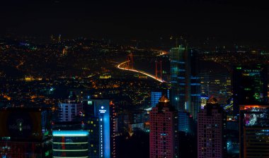İstanbul gece manzarası, yüksek binalar ve plazalar.