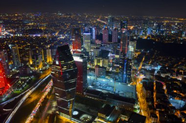 İstanbul gece manzarası, yüksek binalar ve plazalar.