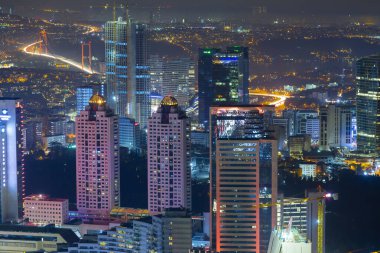 İstanbul gece manzarası, yüksek binalar ve plazalar.
