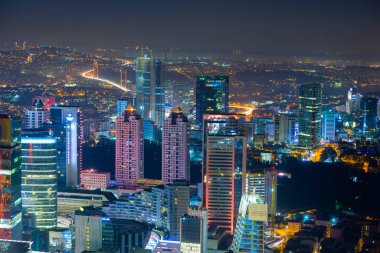 İstanbul gece manzarası, yüksek binalar ve plazalar.