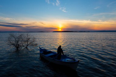 Gölde balık tutmak, gün batımı ve büyük gölde yaşayan insanlar..