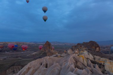 Türkiye 'nin Kapadokya kentindeki sıradışı kayalık manzaraya yüzeysel bir bakış açısı. Kapadokya 'daki peri bacalarıyla mavi gökyüzünde renkli sıcak hava balonları uçuyor..