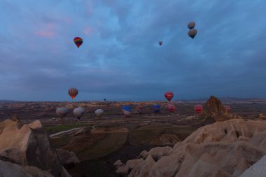 Türkiye 'nin Kapadokya kentindeki sıradışı kayalık manzaraya yüzeysel bir bakış açısı. Kapadokya 'daki peri bacalarıyla mavi gökyüzünde renkli sıcak hava balonları uçuyor..