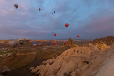 Türkiye 'nin Kapadokya kentindeki sıradışı kayalık manzaraya yüzeysel bir bakış açısı. Kapadokya 'daki peri bacalarıyla mavi gökyüzünde renkli sıcak hava balonları uçuyor..