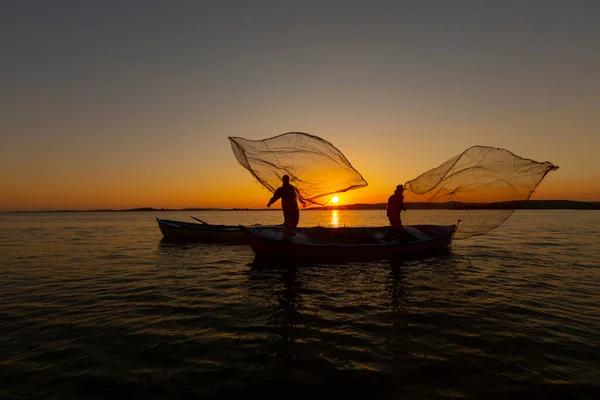 Fishermen throwing fishing net into the sea