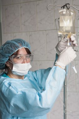 Deneyimli bir hemşire sistem intravenöz infüzyon ve saatler için hazırlar