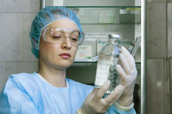 Pielęgniarka uważnie patrząc na leki butelki do infuzji dożylnej kroplówki Obraz Stockowy