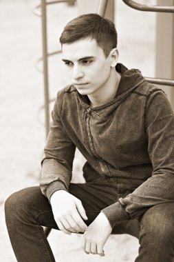 Üzgün dalgın 16 yaşında bir çocuk oyun alanı üzerinde oturur