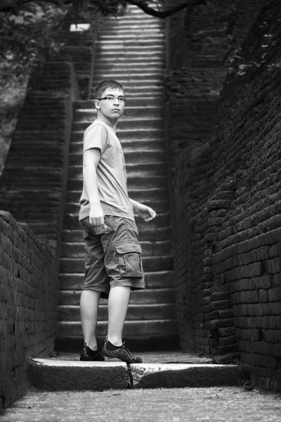 Teenager se dívá na počátku strmého stoupání podél kamenné schodiště — Stock fotografie
