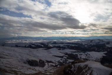 Batan güneş bulutlar aracılığıyla dağ sırasını aydınlatır. Bermamyt platosundan görüntü. Karachay-Cêess Cumhuriyeti, Rusya