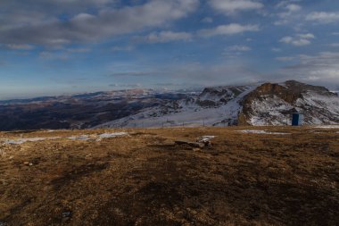 Geçici bir tuvalet, dağlara karşı dikenli tel örgü. Bermamyt platosundan görüntü.