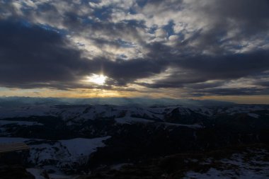 Batan güneş bulutlar aracılığıyla dağ sırasını aydınlatır. Bermamyt platosundan görüntü.