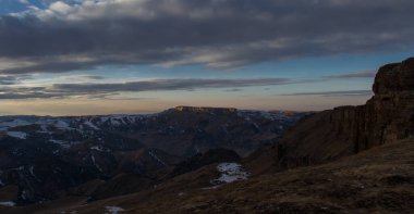 Batan güneş bulutlar aracılığıyla dağ sırasını aydınlatır. Bermamyt platosundan görüntü. Karachay-Cêess Cumhuriyeti, Rusya
