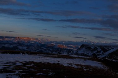 Batan güneş bulutlar aracılığıyla dağ sırasını aydınlatır. Bermamyt platosundan görüntü.