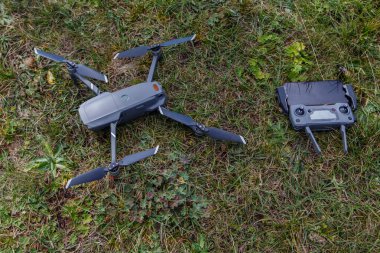Kuadkopter ve uzaktan kumanda yeşil gra üzerinde yatıyor.