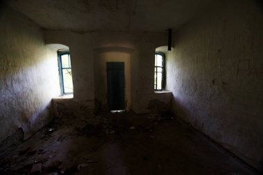 Terk edilmiş bir binada iki parlak pencere ve aralarında karanlık bir kapı.