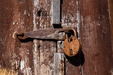 Eski bir kilit ahşap bir kapının üzerinde boyası soyulmuş.