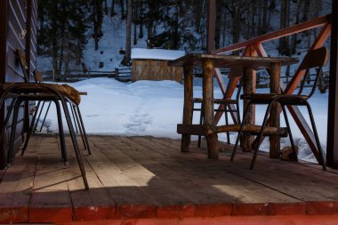Kabataslak kütüklerden yapılmış bacakları ve eski sandalyeleri olan bir masa. 