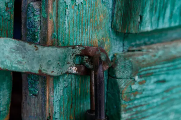 Eski bir kilit ahşap bir kapının üzerinde boyası soyulmuş.