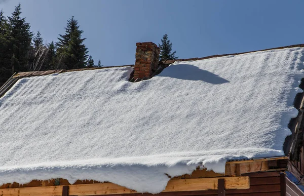 Tuğla baca ve tahta çatı karla kaplı.