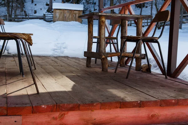 a table with legs made of rough-hewn logs and old chairs on the