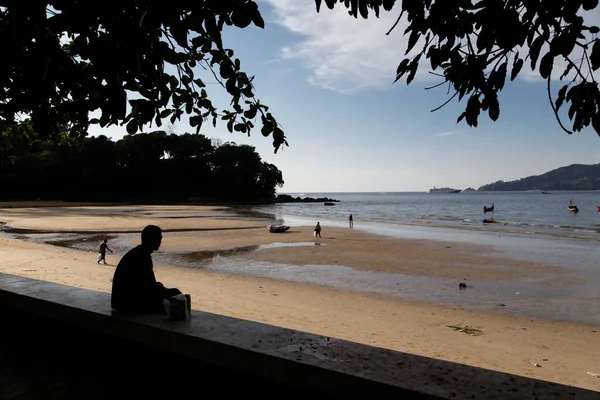 Outline of a man looking out at the sea at low tide