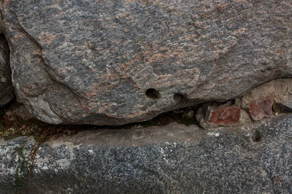 Gri granitte birkaç yuvarlak delik var.