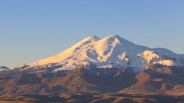 Elbrus bulutsuz bir sabahta güneşin doğuşunun pembe ışınlarında. Manzara Bermamyt platosundan, Karachay-Cêess Cumhuriyeti, Rusya