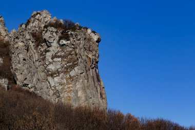 Sonbahar ormanıyla çevrili açık mavi gökyüzünün arka planında bir kaya. Beshtau Dağı, Kafkasya, Rusya