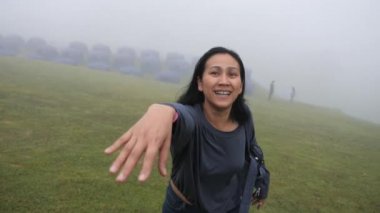 Asyalı bir kadın, dağlarda yürümek için sevgilisinin elini tutuyor.