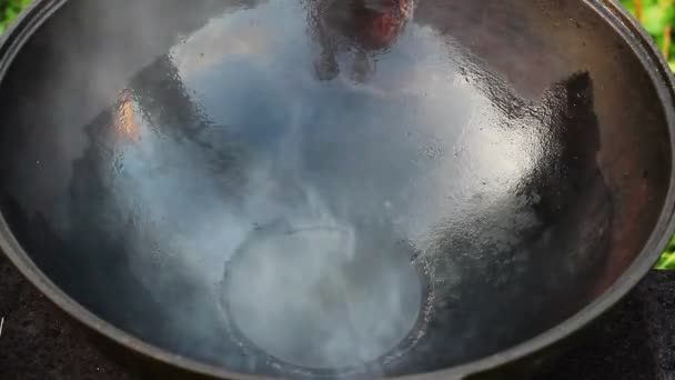 Óleo e gordura são aquecidos em uma panela aberta. caldeirão de ferro fundido grande em uma fogueira aberta. panela vazia — Vídeo de Stock