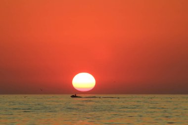İnsan, günbatımında arka planda su bisikleti sürerken hayattan zevk alır.