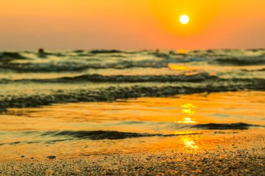 Sahilde ıslak deniz kumu arka planda güzel altın gün batımı. Gün batımında okyanus kıyısındaki deniz kumlarını kapatın. Gün batımında deniz manzarası. Sahilde gün batımında altın ıslak kum. 