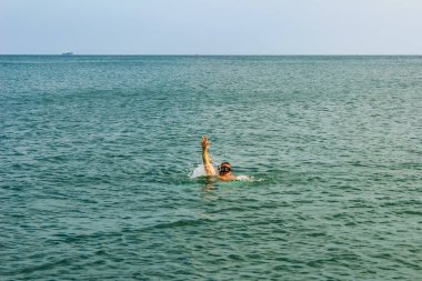Dalış maskeli adam açık denizde zafer işareti gösteriyor. Barış işareti