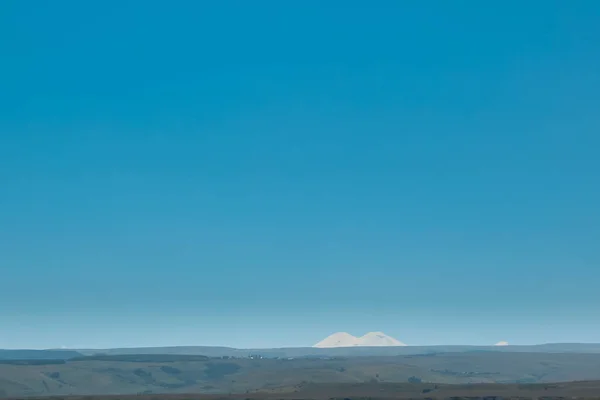 Doble pico de Elbrus en la distancia contra el cielo azul. Rusia, Cáucaso — Foto de Stock