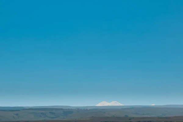 Doble pico de Elbrus en la distancia contra el cielo azul. Rusia, Cáucaso — Foto de Stock