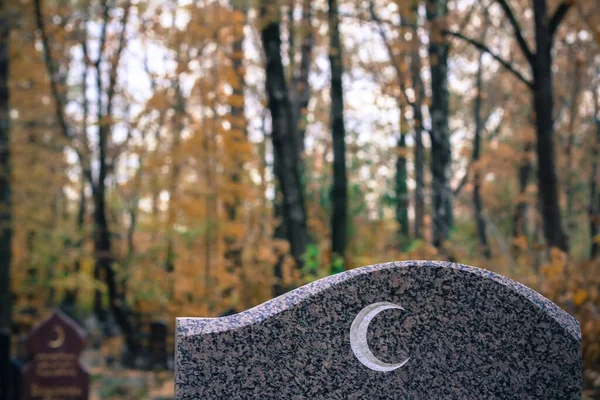 Granit mezar taşında geleneksel İslami hilal sembolü. Müslüman mezarı sonbahar mezarlığında.