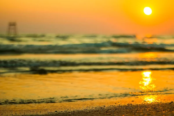 Влажный морской песок на пляже на фоне красивого золотого заката. Закрыть морской песок на берегу океана во время заката. Золотой мокрый песок на пляже на фоне заката. — стоковое фото