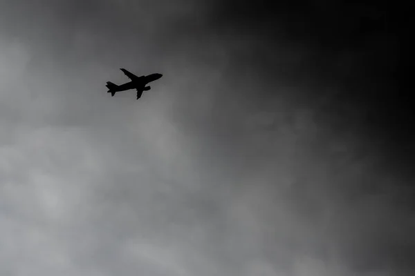 Uçak fırtınaya doğru uçuyor. Silüet uçaklar gök gürültülü bulutlarda uçar. Uçak kazası tehlikesi kavramı. Bir kasırganın arka planında yolcu uçağı