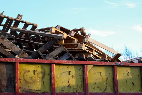 Usuwanie śmieci. Kupa drewnianych odpadów paletowych na tle błękitnego nieba — Zdjęcie stockowe
