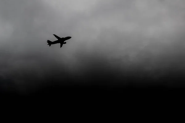 Uçak fırtınadan uzaklaşıyor. Silüet uçak fırtına bulutlarından kaçıyor. Uçak kazası tehlikesi kavramı. Bir kasırganın arka planında yolcu uçağı