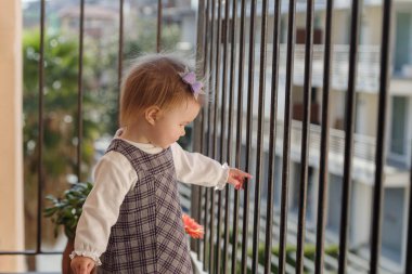 Kız balkonun korkuluğunda duruyor.