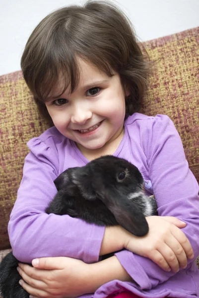 Preschool girl playing with rabbit — Stock Photo, Image